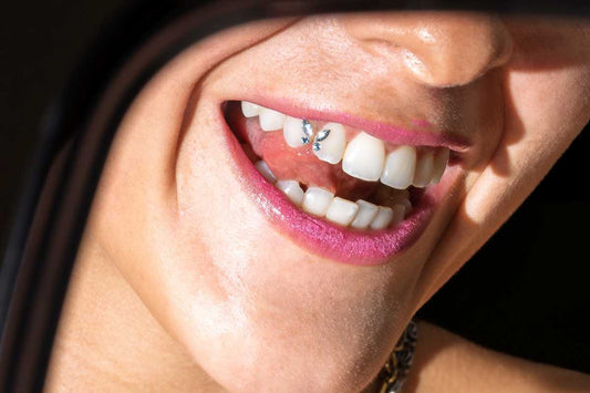 A person smiling in the rear view mirror of a car with the butterfly design tooth gem trend